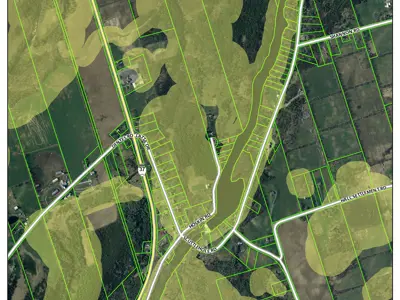 Aerial view of a patterned landscape of fields and roads, highlighting green and brown agricultural areas with marked property boundaries.