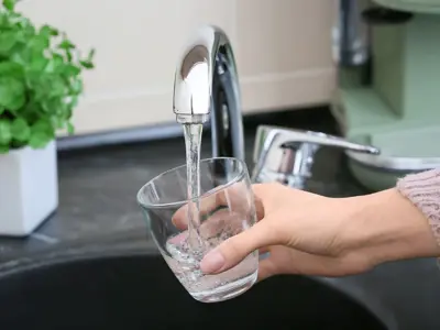 Glass cup being filled with water at a tap